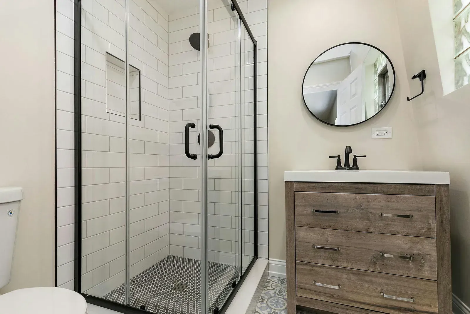 A bathroom with a toilet , sink , shower and mirror.