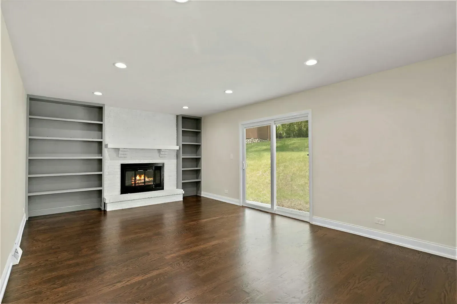 An empty living room with a fireplace and sliding glass doors.