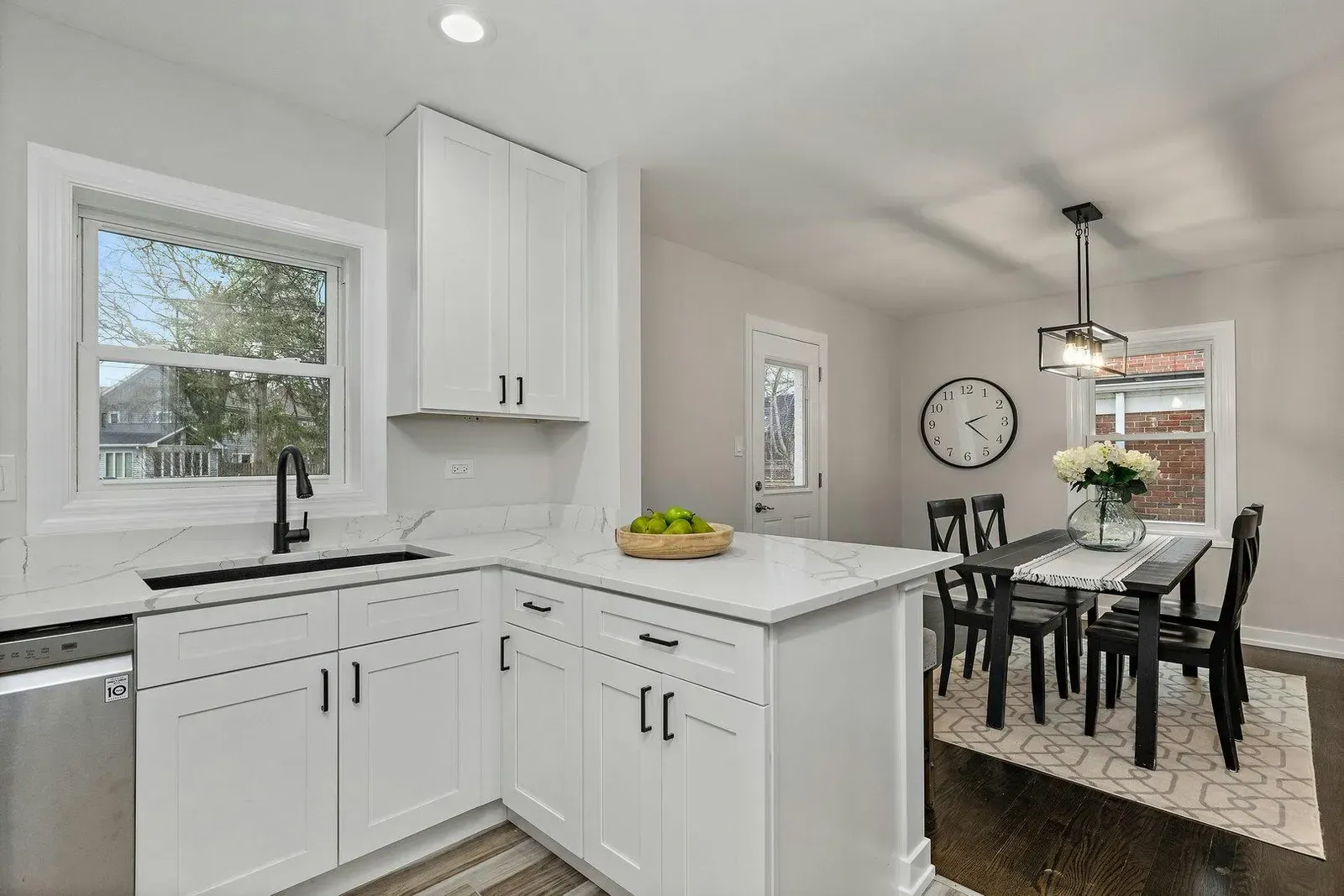A kitchen with white cabinets , a sink , a table and chairs.