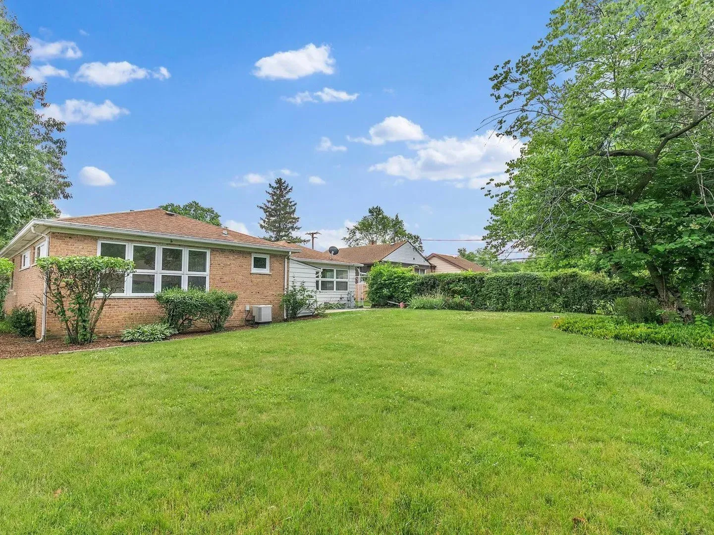 A brick house with a large lawn in front of it.