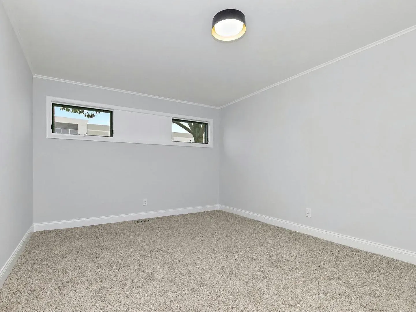 An empty room with a window and a light on the ceiling.
