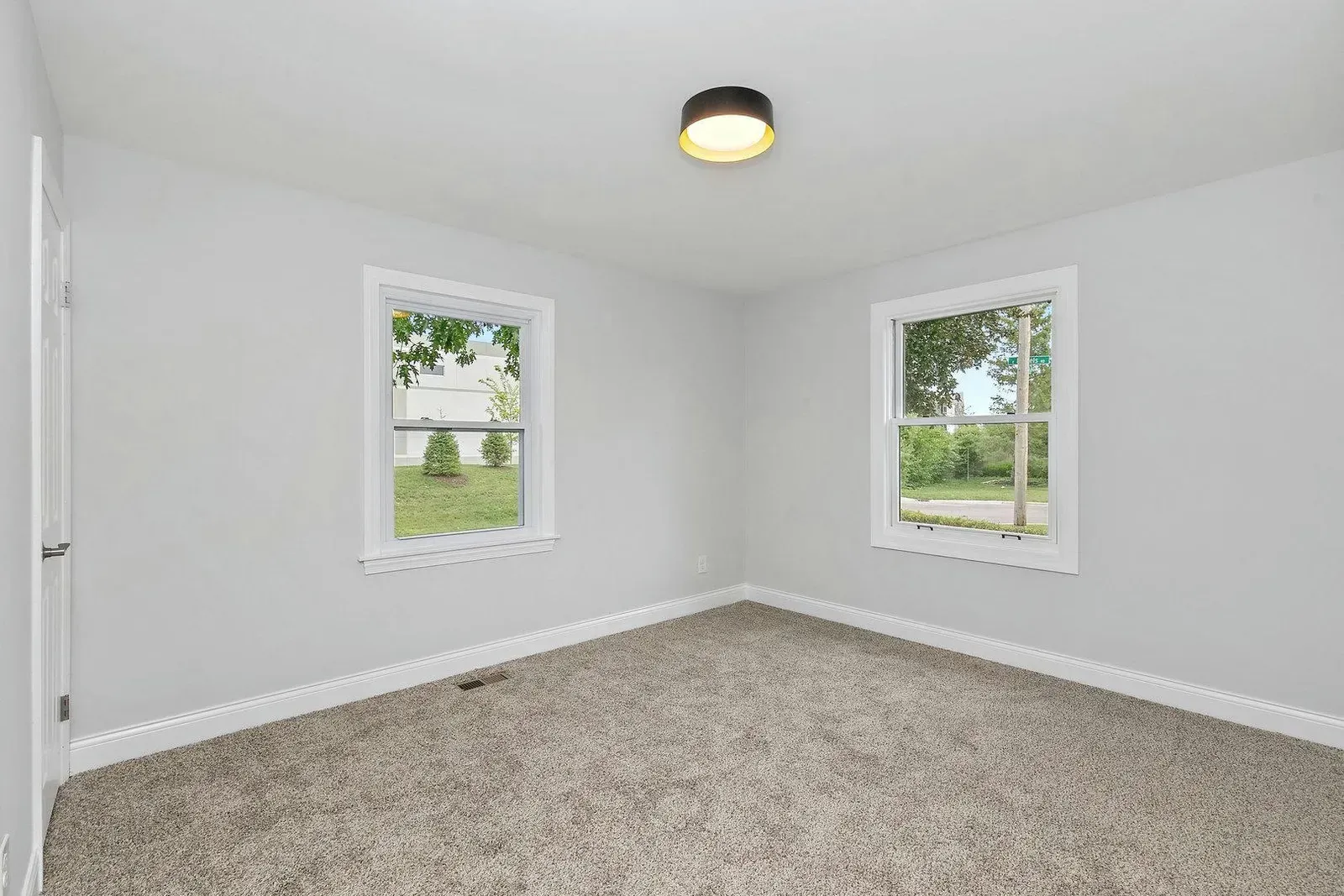 An empty room with two windows and a ceiling light.
