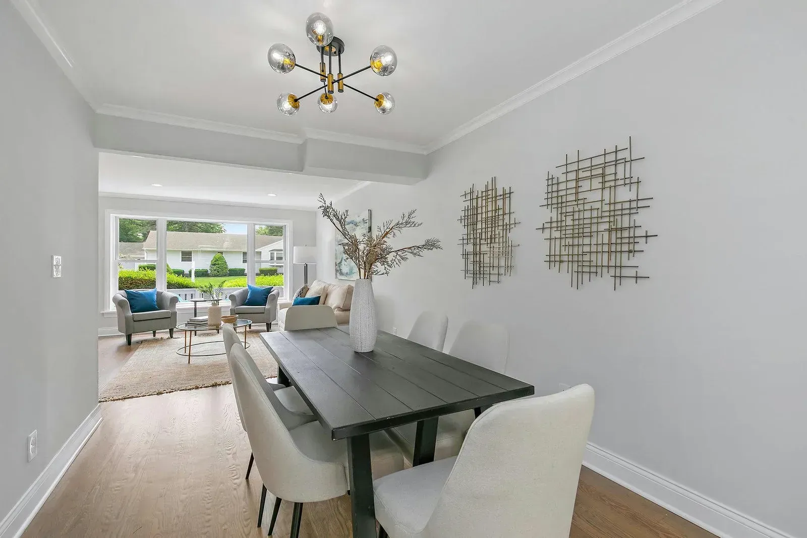 A dining room with a table and chairs and a living room in the background.