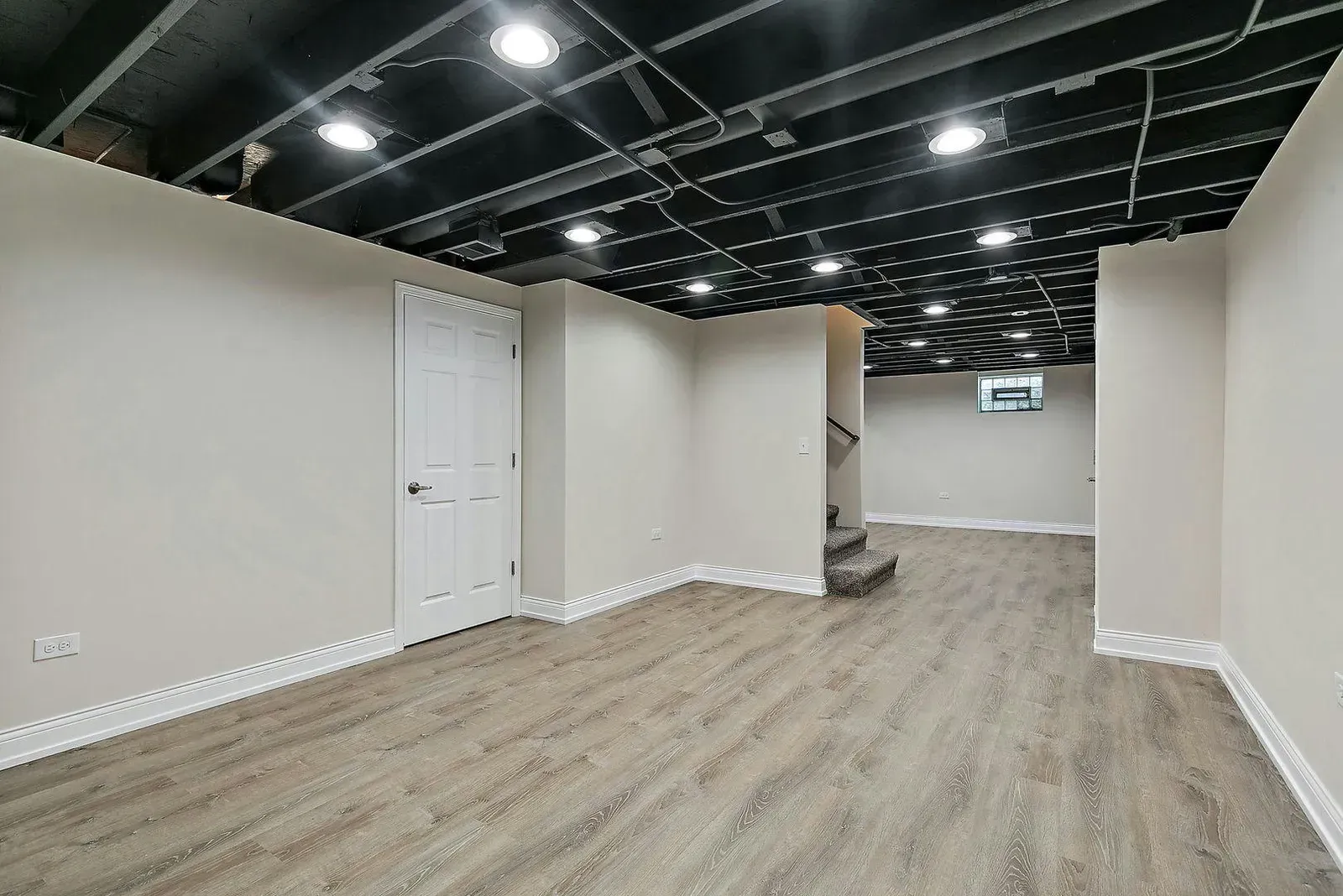 An empty basement with hardwood floors and a black ceiling.