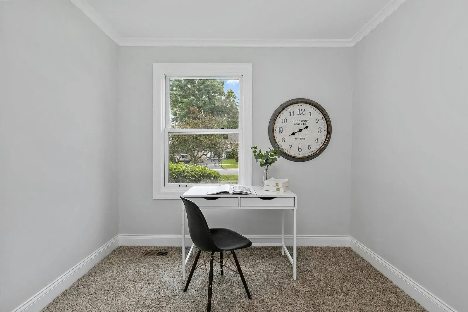 There is a clock on the wall above the desk in the room.