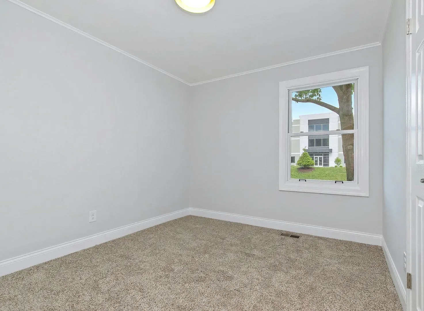 An empty room with a window and a carpeted floor.