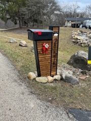 A mailbox is sitting on the side of a road next to a grassy field.