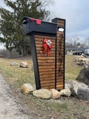 A mailbox with a red bow on it is sitting on the side of a road.