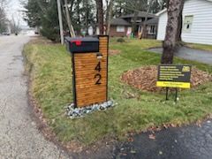 A mailbox is sitting on the side of the road next to a house.