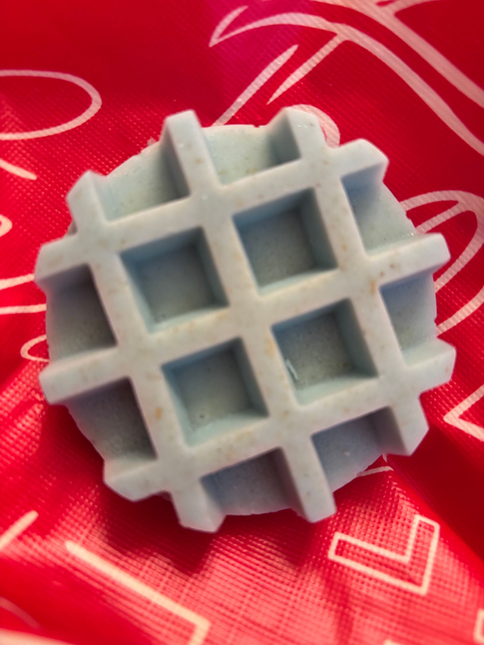 Blue, waffle-shaped item on a red background.