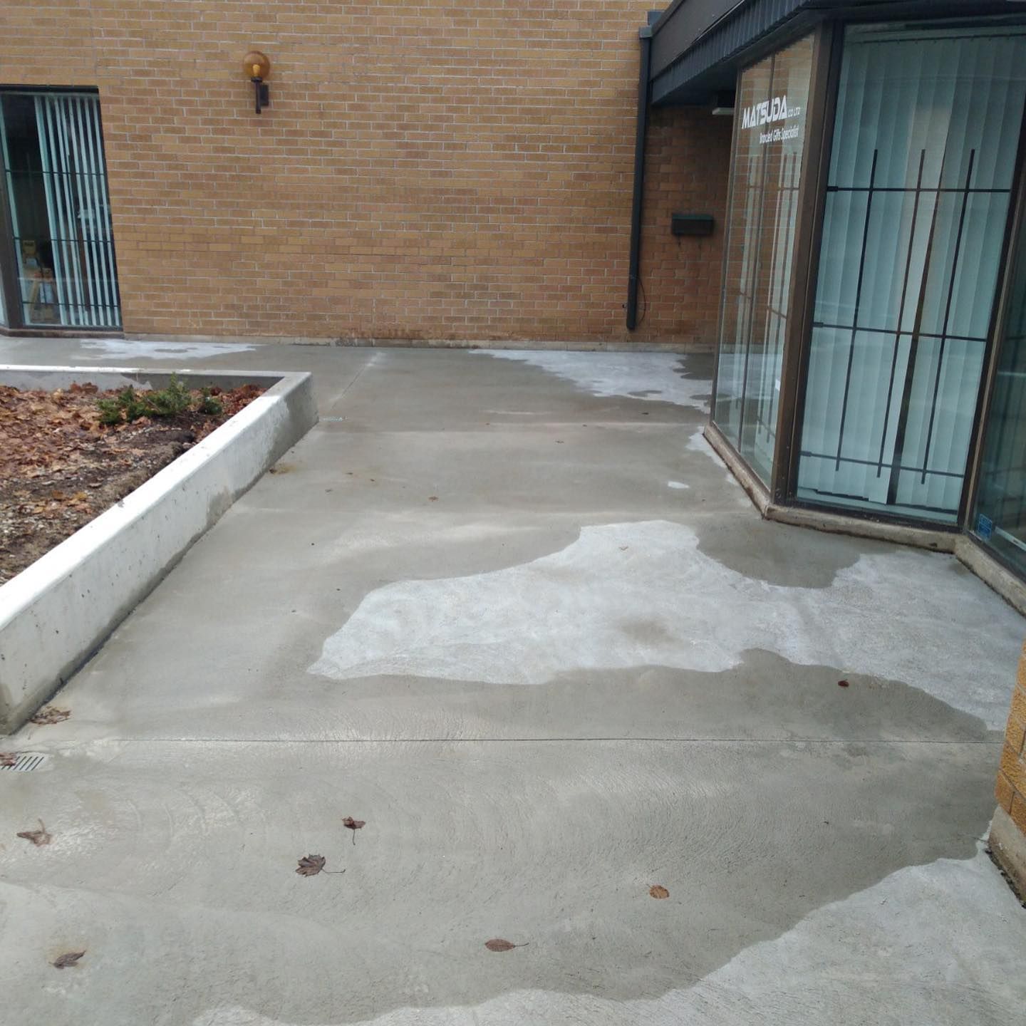 A brick building with a concrete walkway in front of it