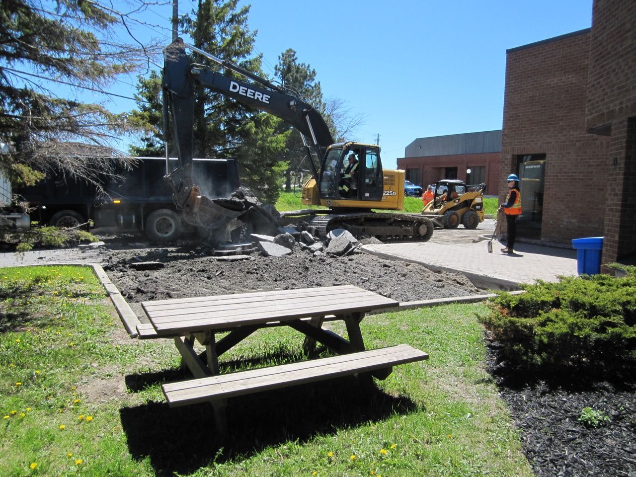 A picnic table in front of a deere excavator