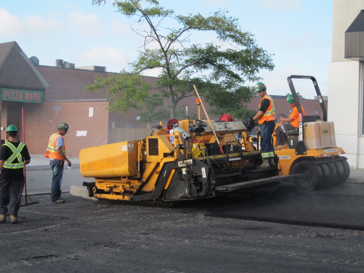 A group of construction workers are working on a road in front of a 7 eleven