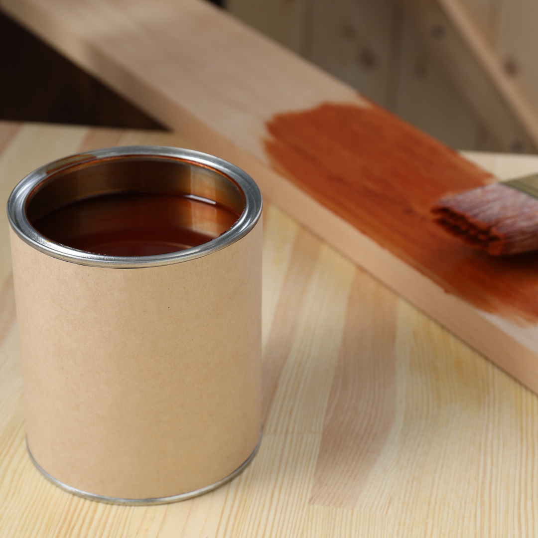 A can of brown paint sits on a wooden table