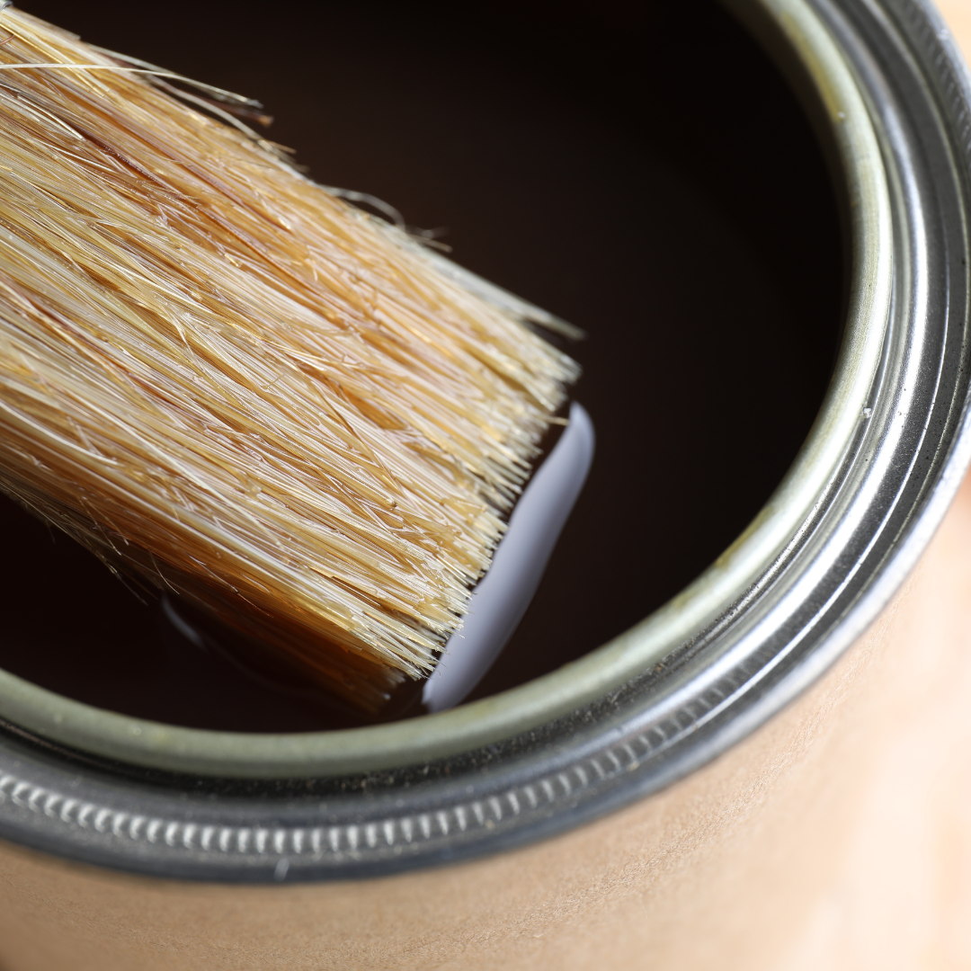 A can of brown paint with a brush in it