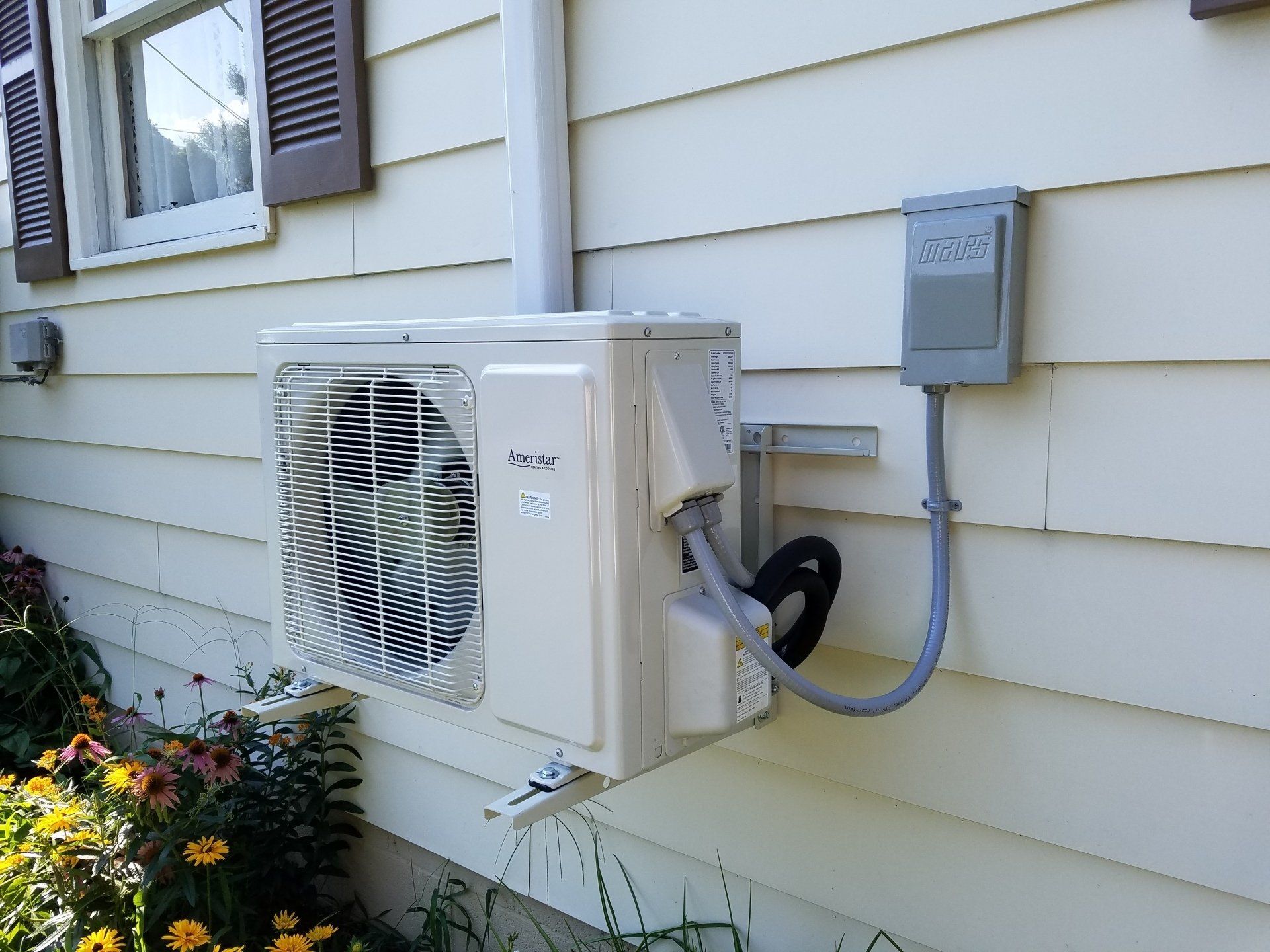 A white air conditioner is mounted on the side of a house.