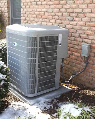 An air conditioner is sitting on the side of a brick building.