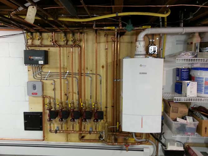 A white boiler is mounted to a wall in a basement