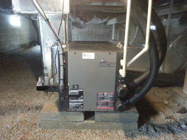 An air conditioner is sitting on a brick in a basement.