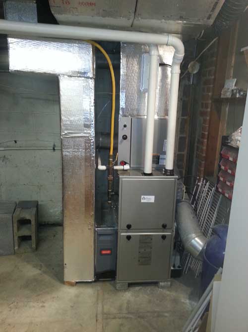 An air conditioner is sitting in a basement next to a wall.