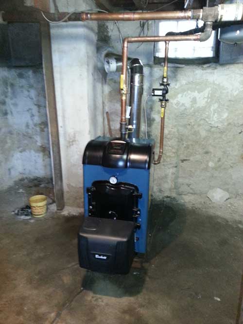 A blue boiler in a basement with copper pipes