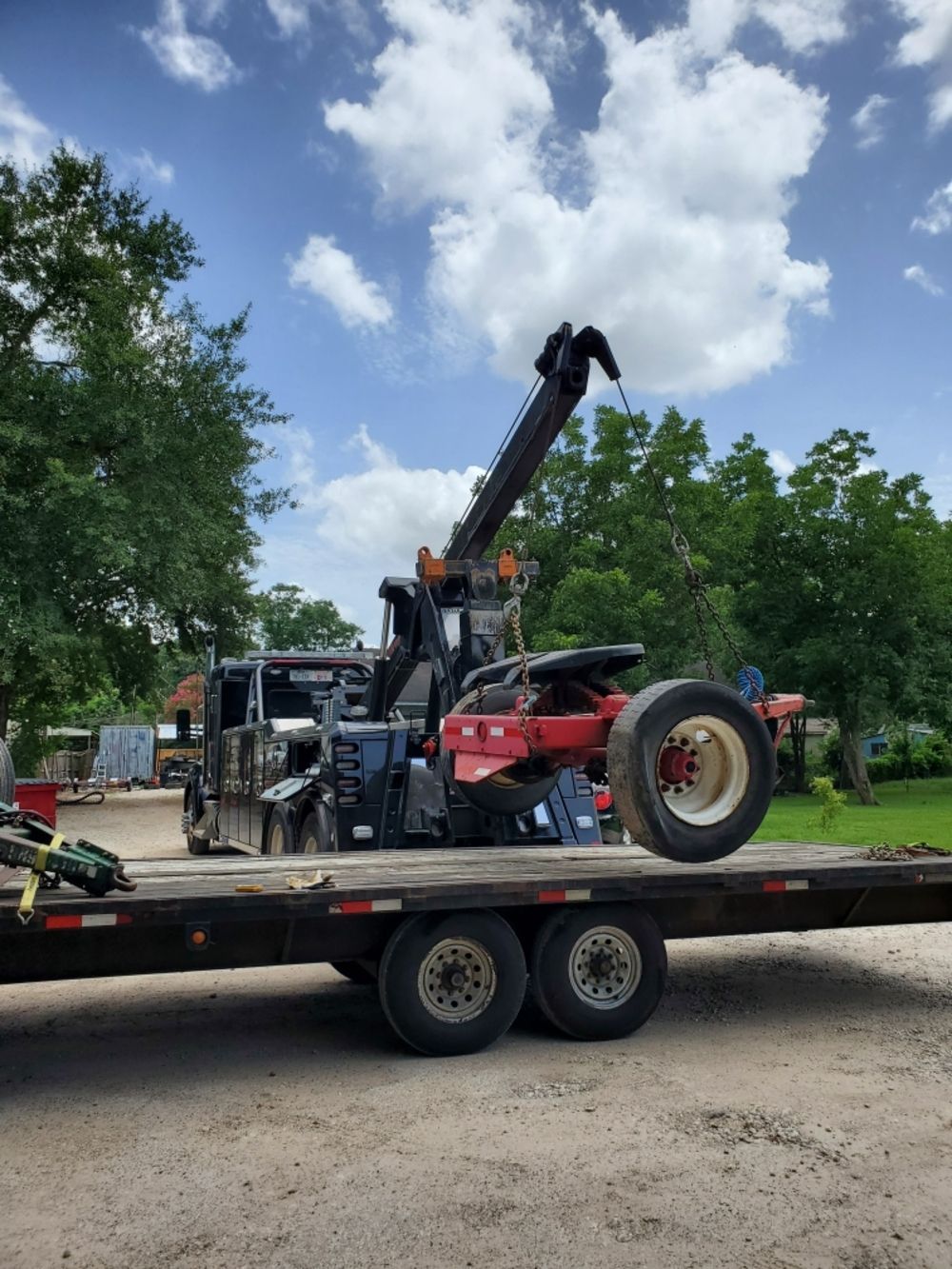 A tow truck is carrying a tractor on a flatbed trailer.