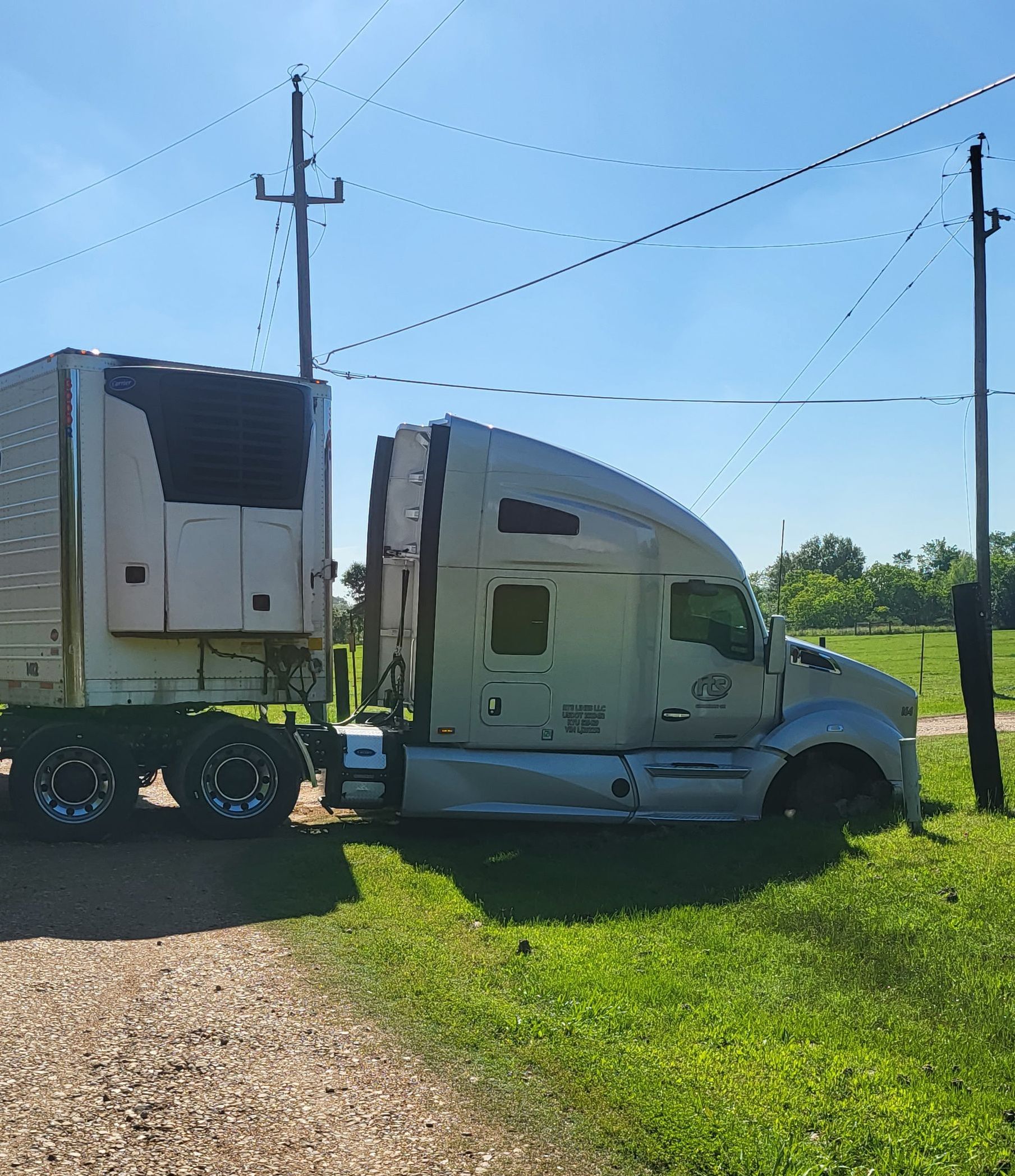 A semi truck with a trailer attached to it is parked in a grassy field.