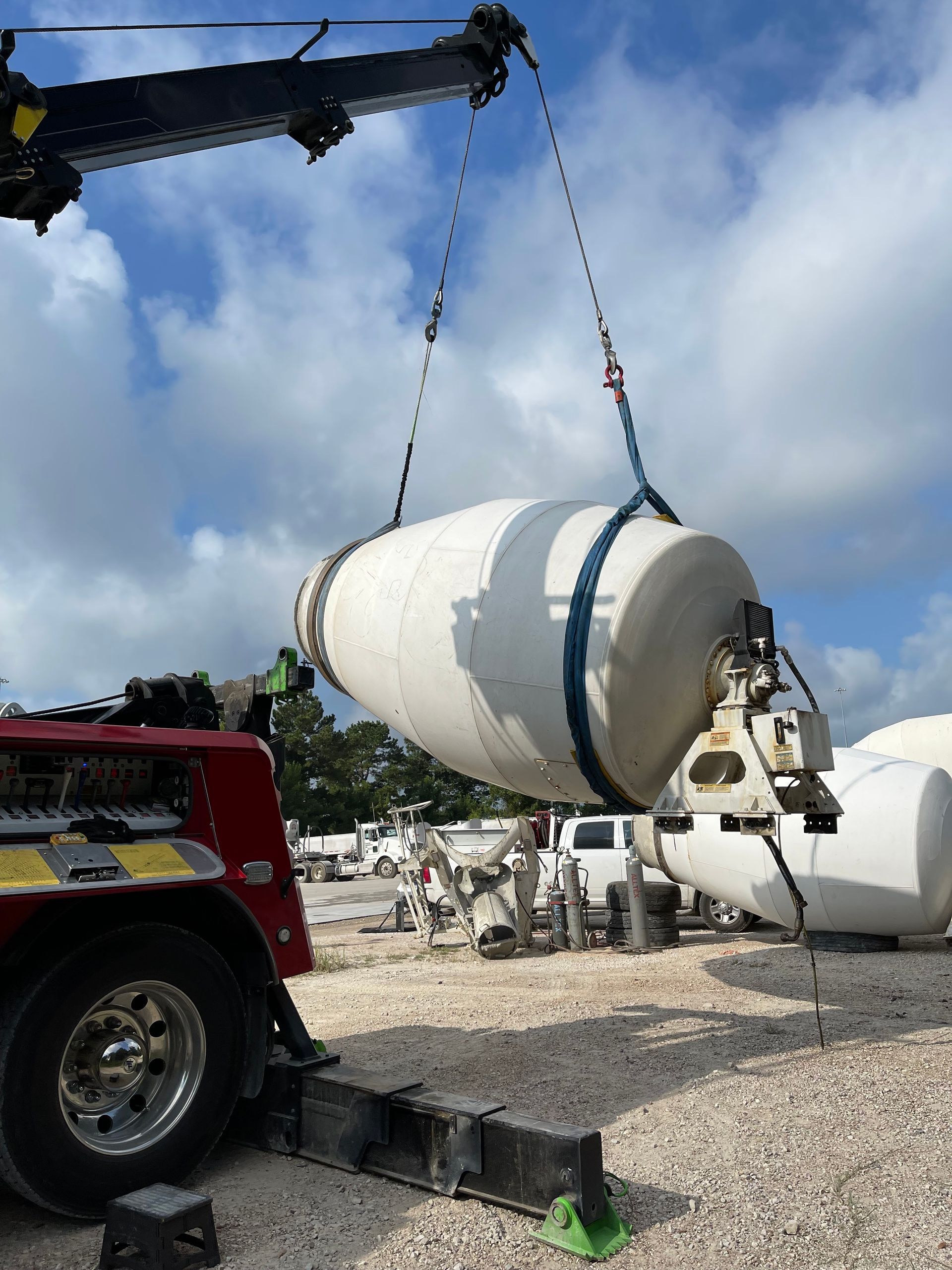 A concrete mixer is being lifted by a crane.