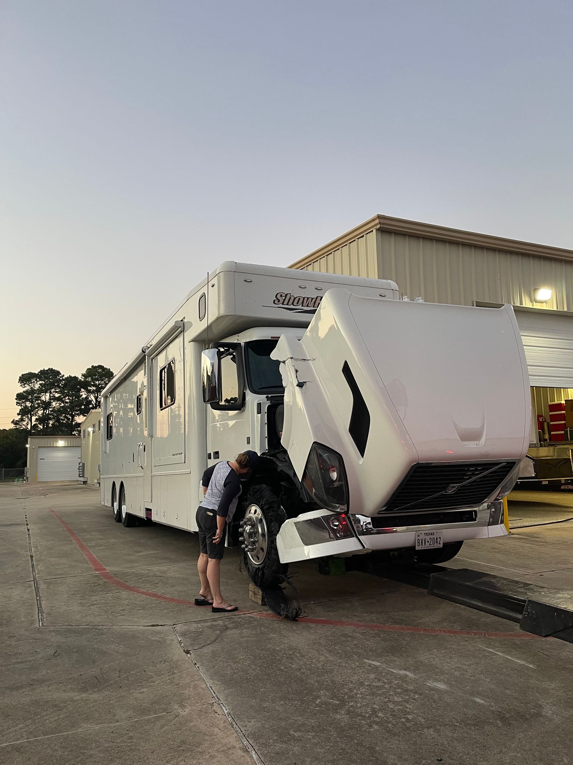 A man is standing next to a rv with its hood up.