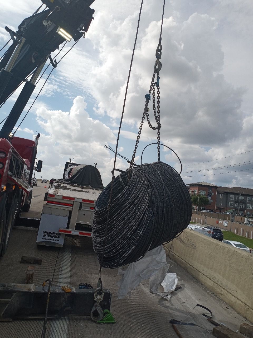 A large spool of wire is being lifted by a crane.