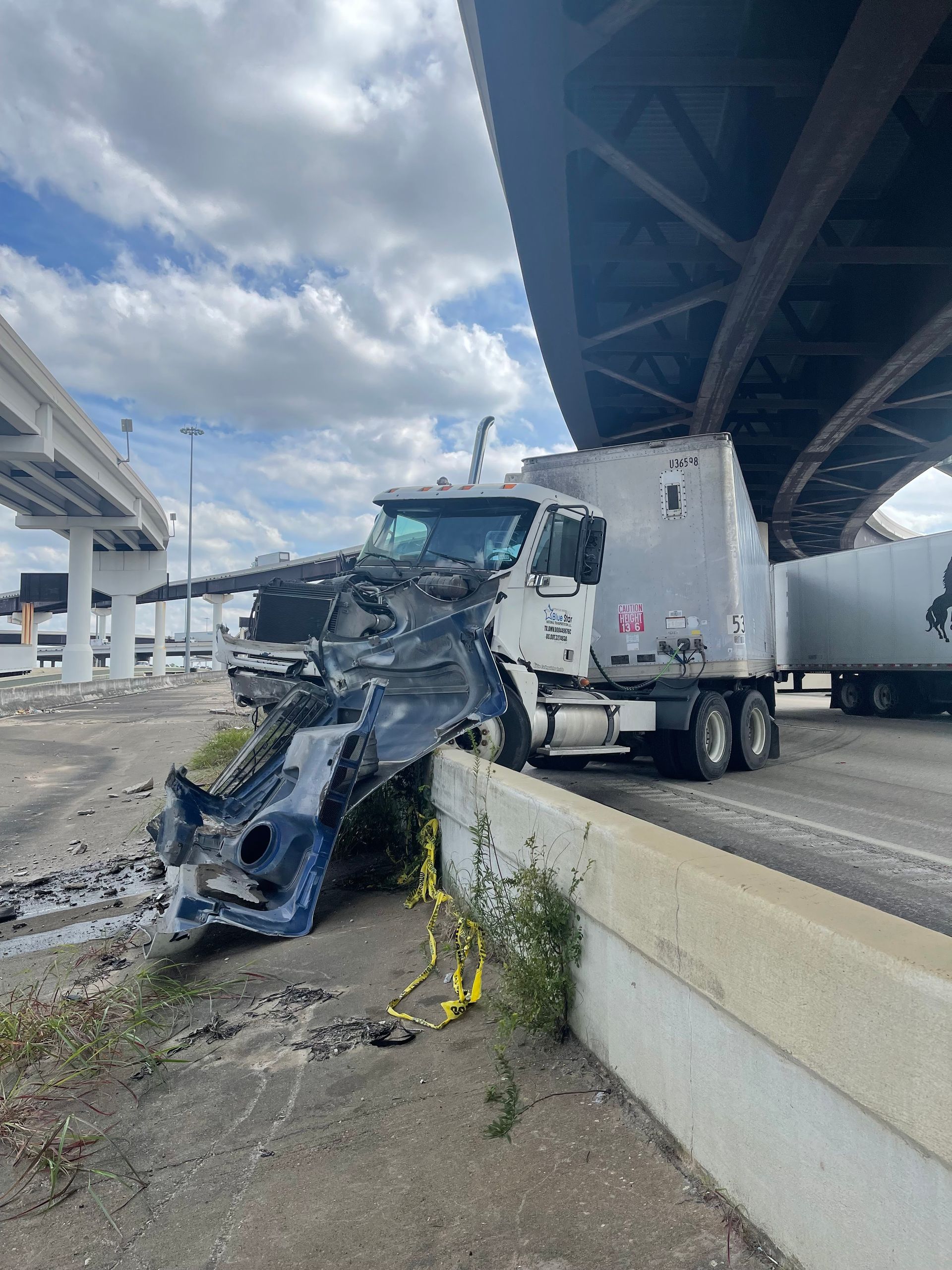 A semi truck has crashed into a car on a highway.