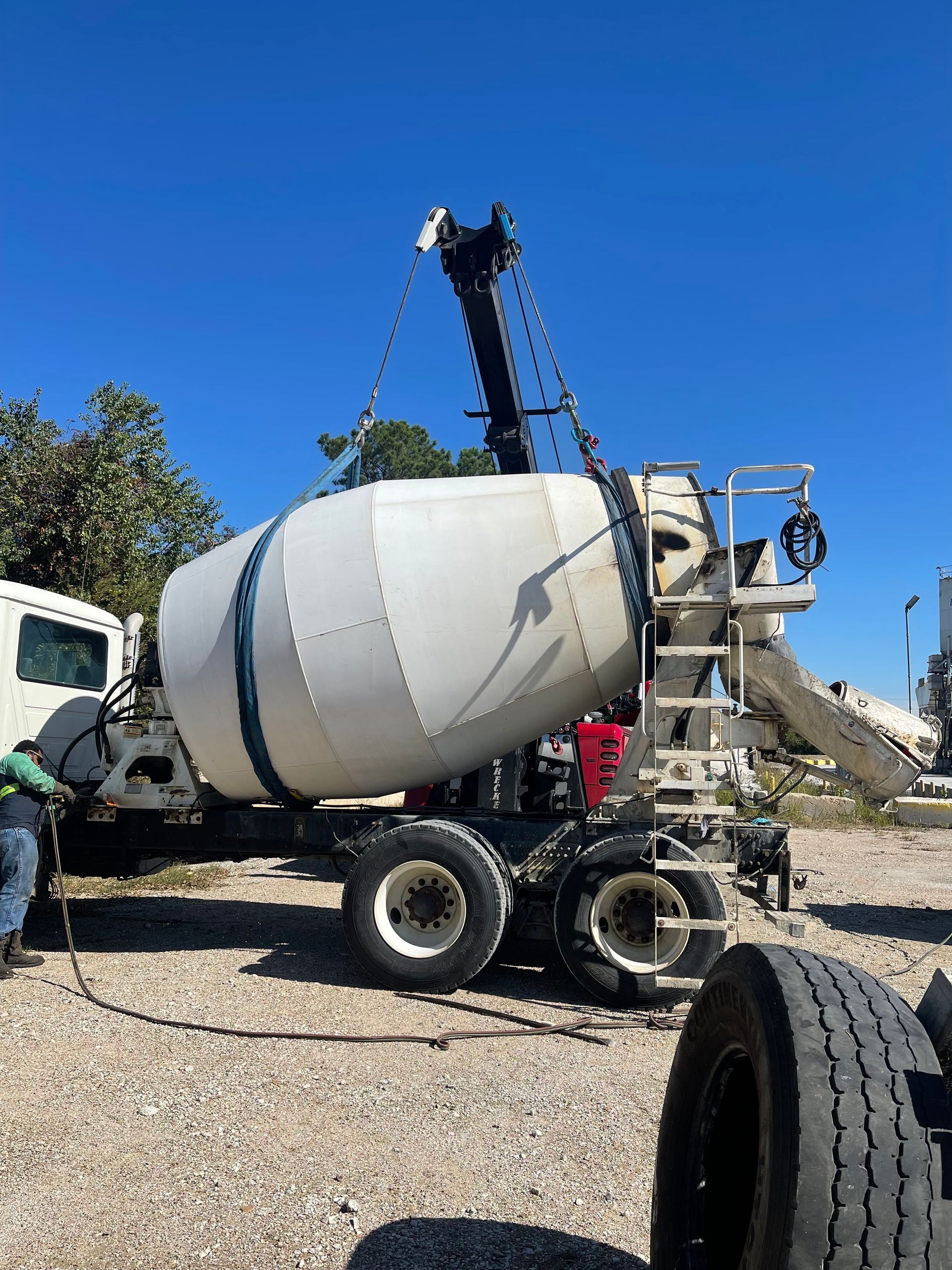 A concrete mixer truck is being lifted by a crane.