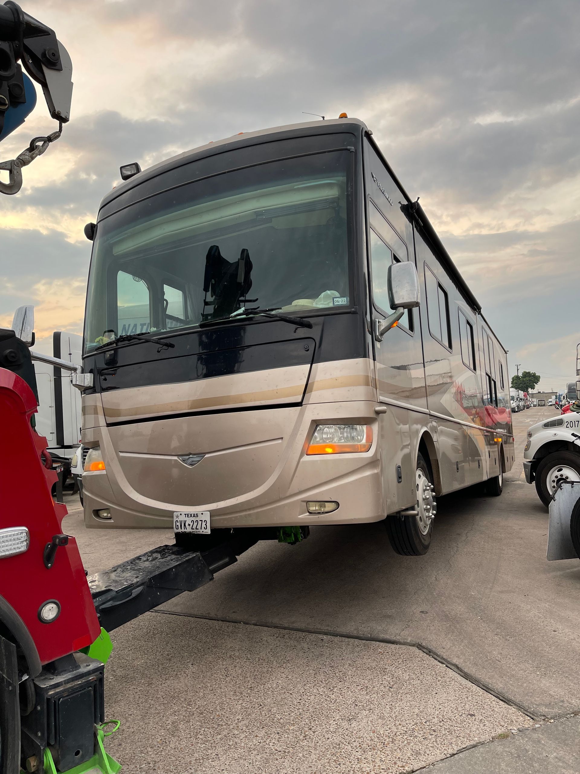 A large rv is being towed by a tow truck.