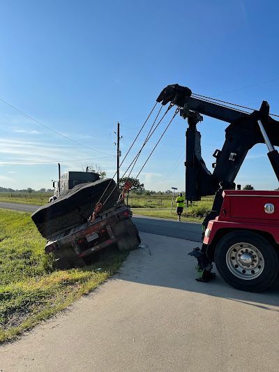 A tow truck is towing a truck that has fallen off the road.