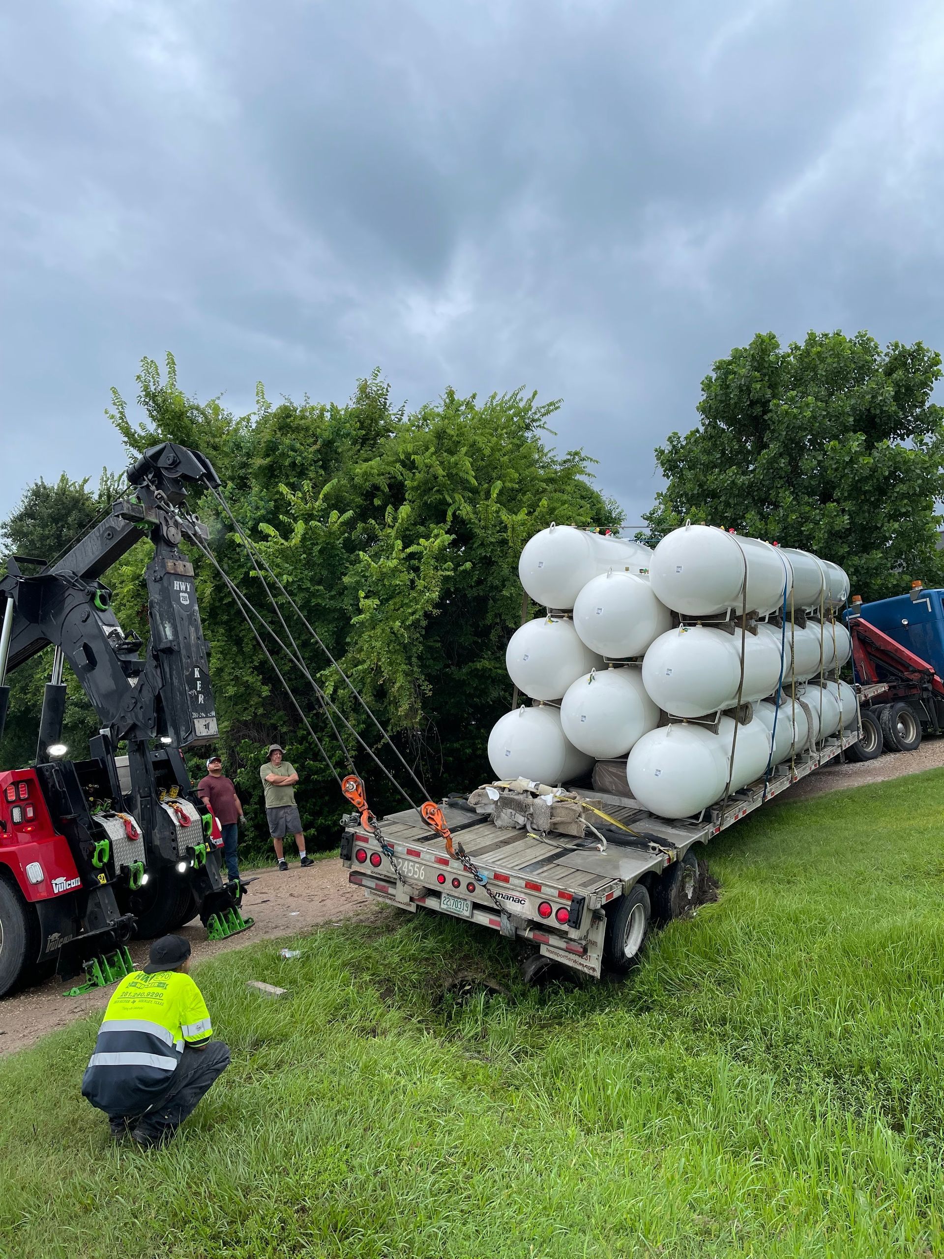 A tow truck is carrying a stack of propane tanks on a trailer.