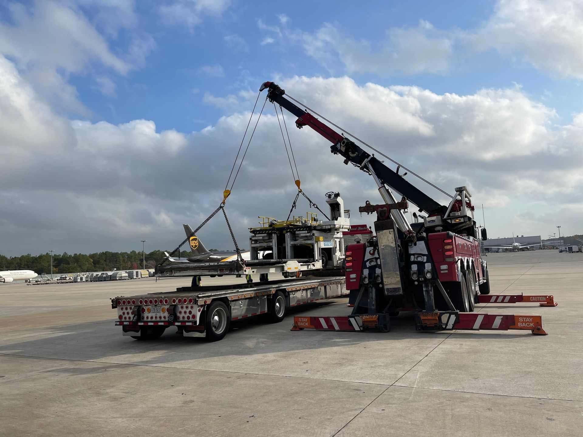 A tow truck is lifting a plane on a trailer