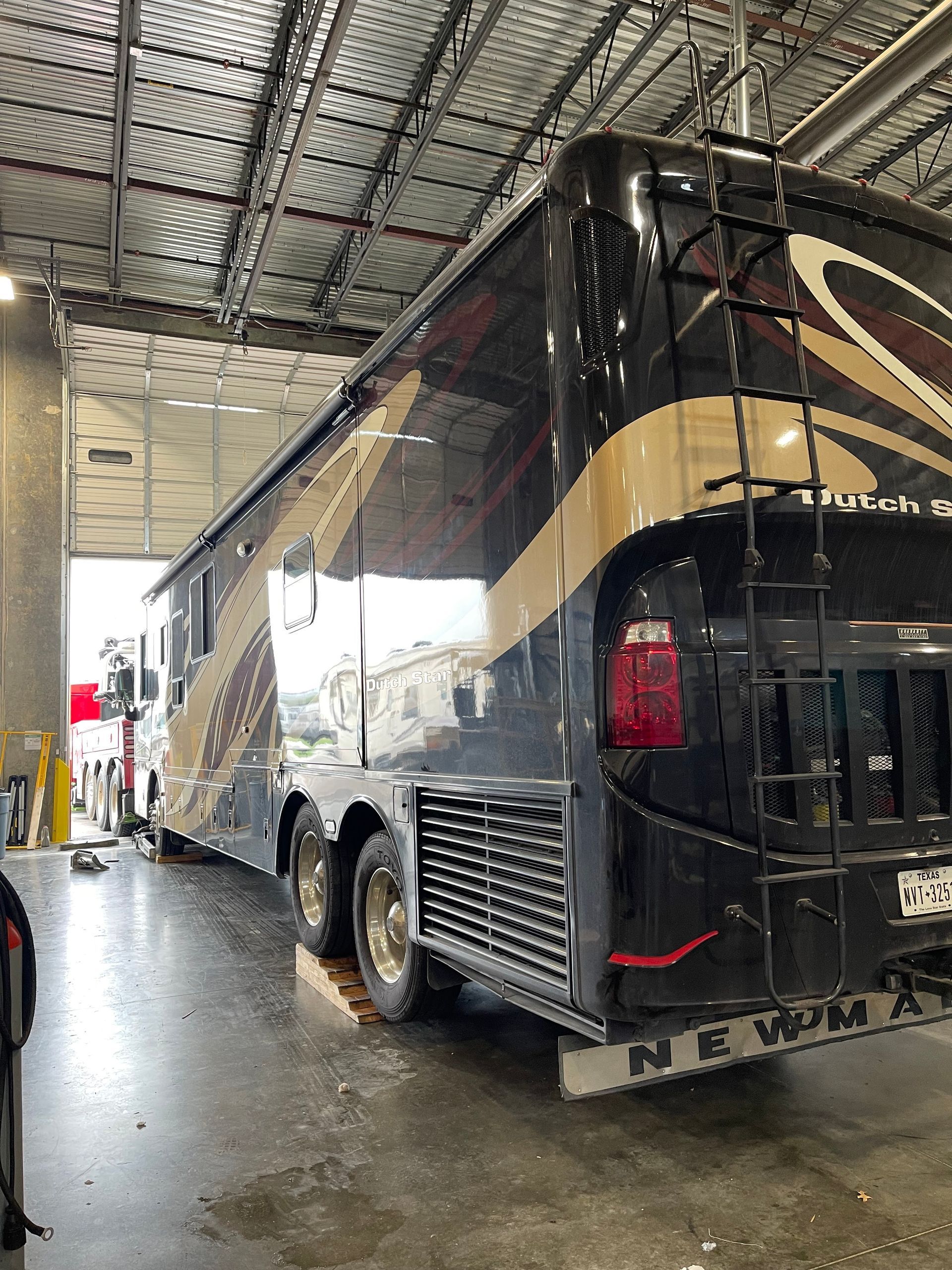 A large black and gold bus is parked in a garage.