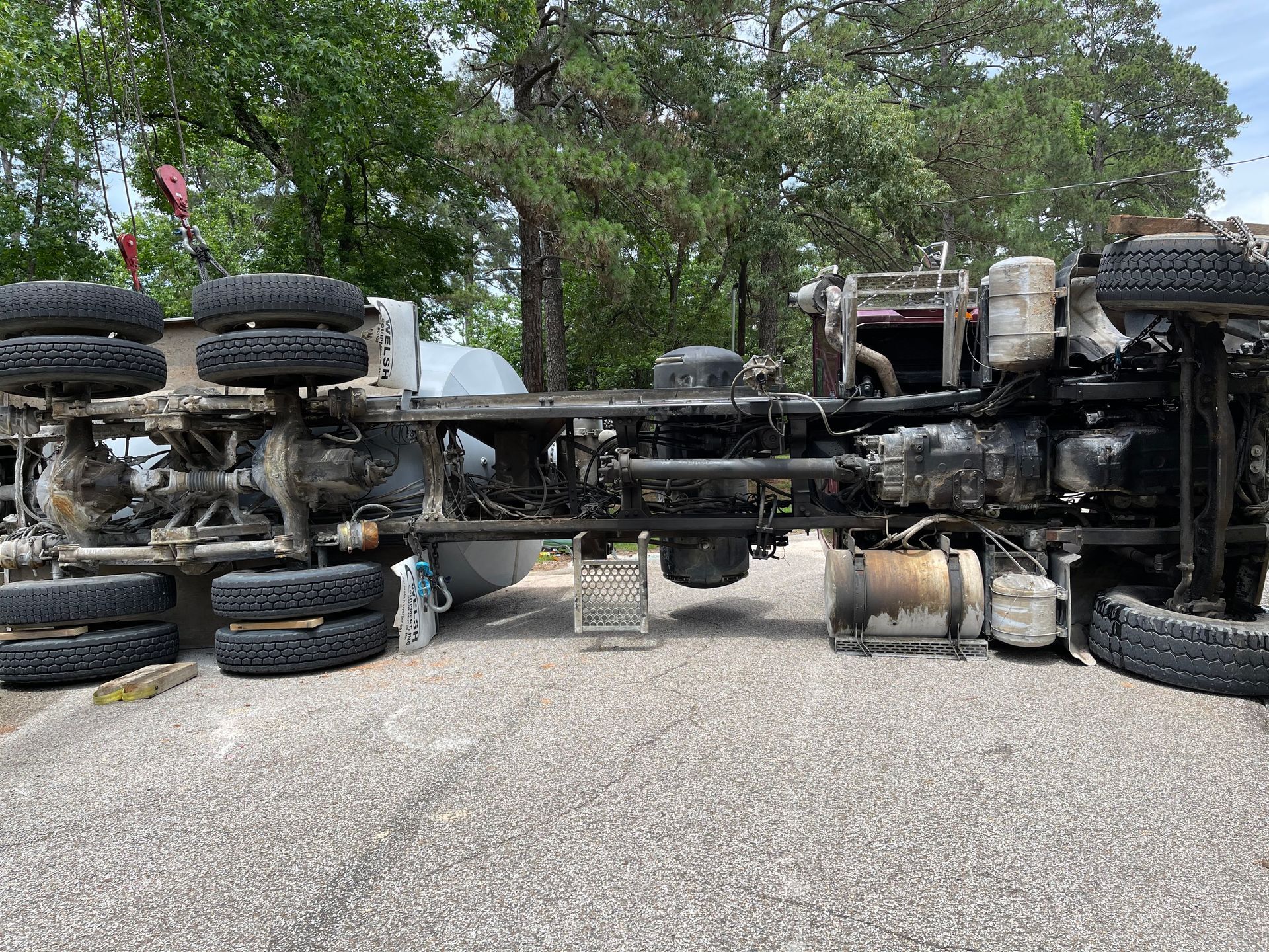 A semi truck is laying on its side in a parking lot.