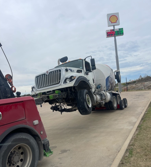 A concrete mixer truck is being towed by a tow truck