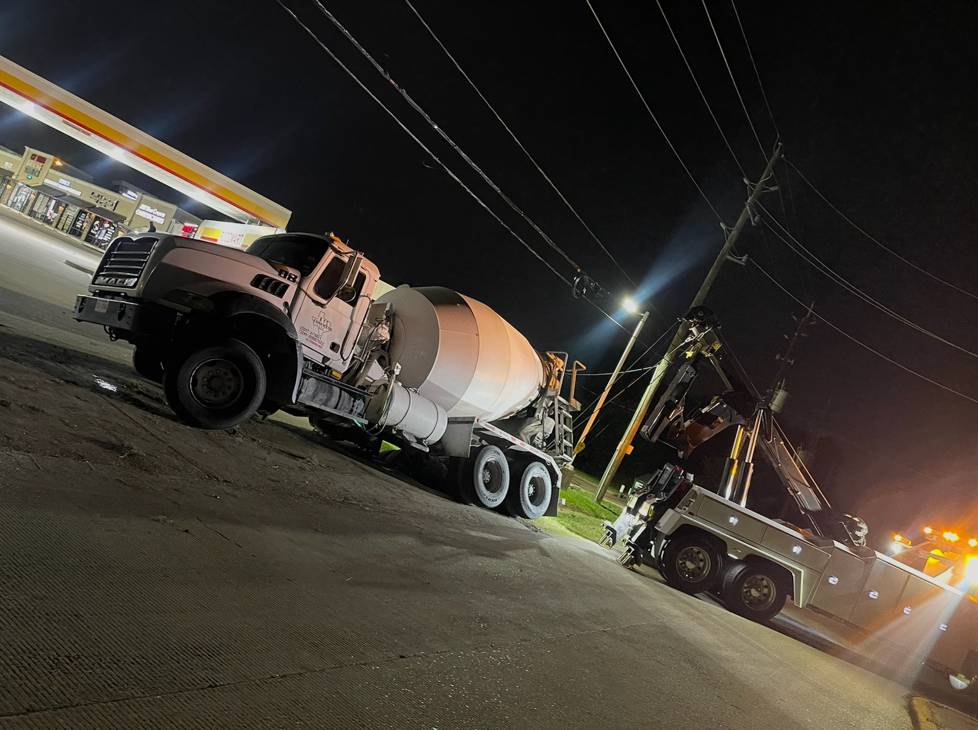 A concrete mixer truck is parked on the side of the road at night.