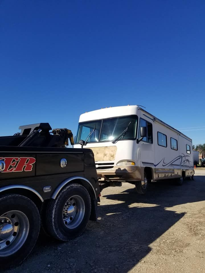 A silver semi truck is parked in a grassy field.