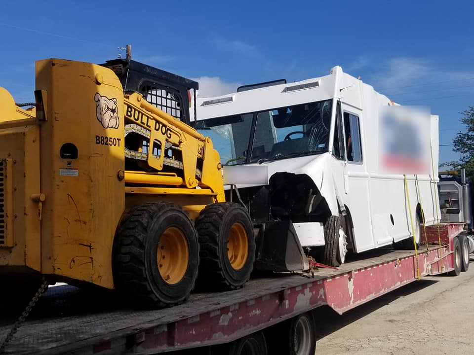 A bulldozer and a white truck are sitting on top of a trailer.