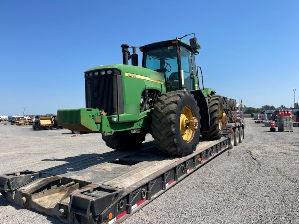 A green john deere tractor is sitting on top of a trailer.