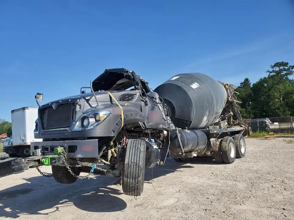 A concrete mixer truck is sitting in a dirt lot.