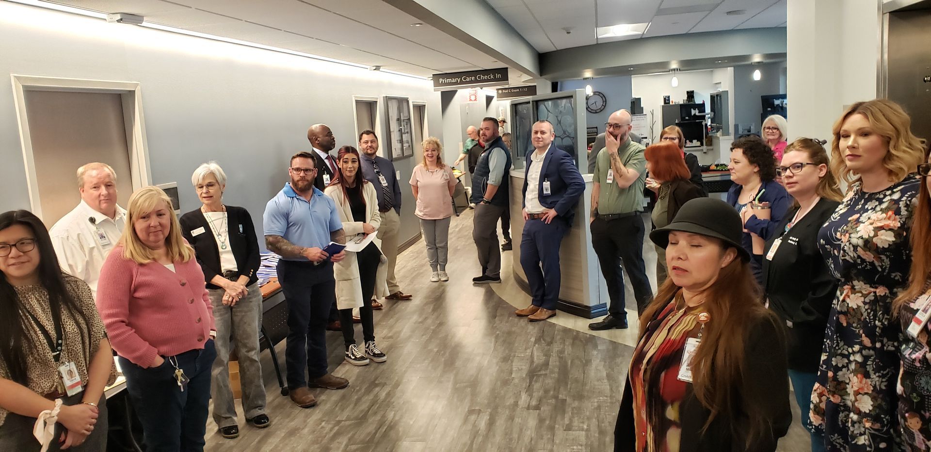 A group of people standing in a hallway, some wearing lanyards, appearing to be an event or tour.