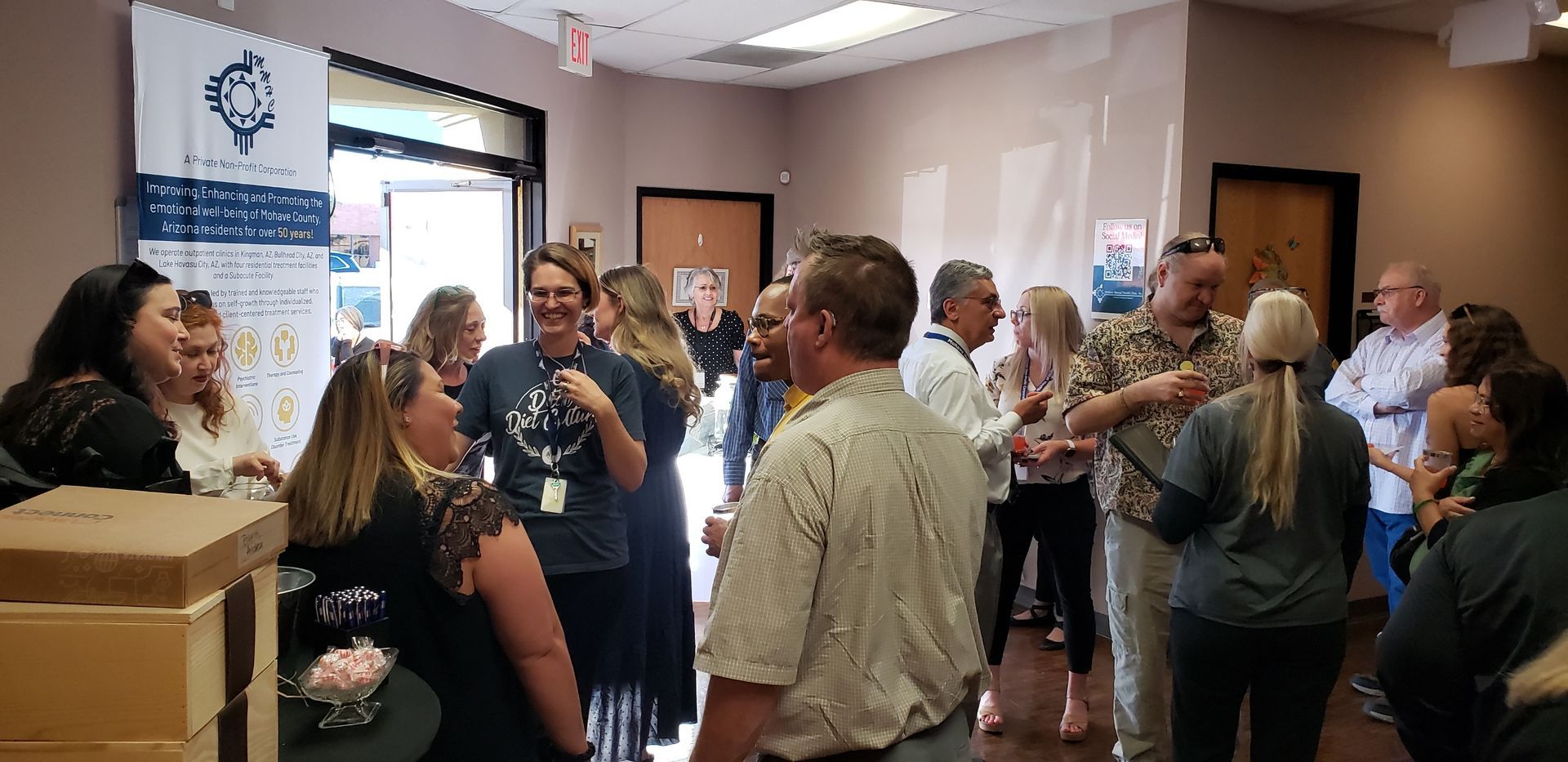People gathered in an interior space, talking and smiling. Some are wearing name tags.