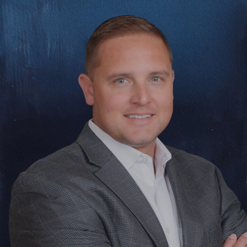 Man in gray suit smiles, facing forward against a dark blue background.