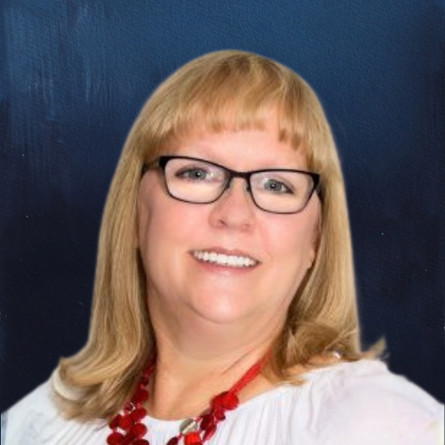 Woman with blonde hair and glasses smiles; wearing a red necklace and white top, against a blue background.