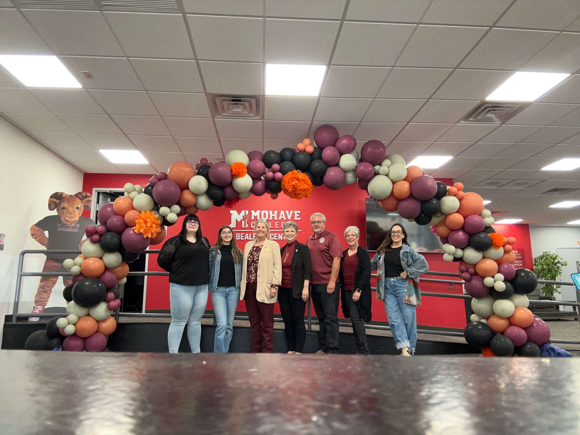 Group of people standing in front of a balloon arch at an event with Mohave.