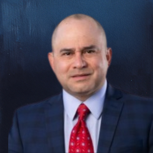 Bald man in suit and red tie, facing the camera with a neutral expression.